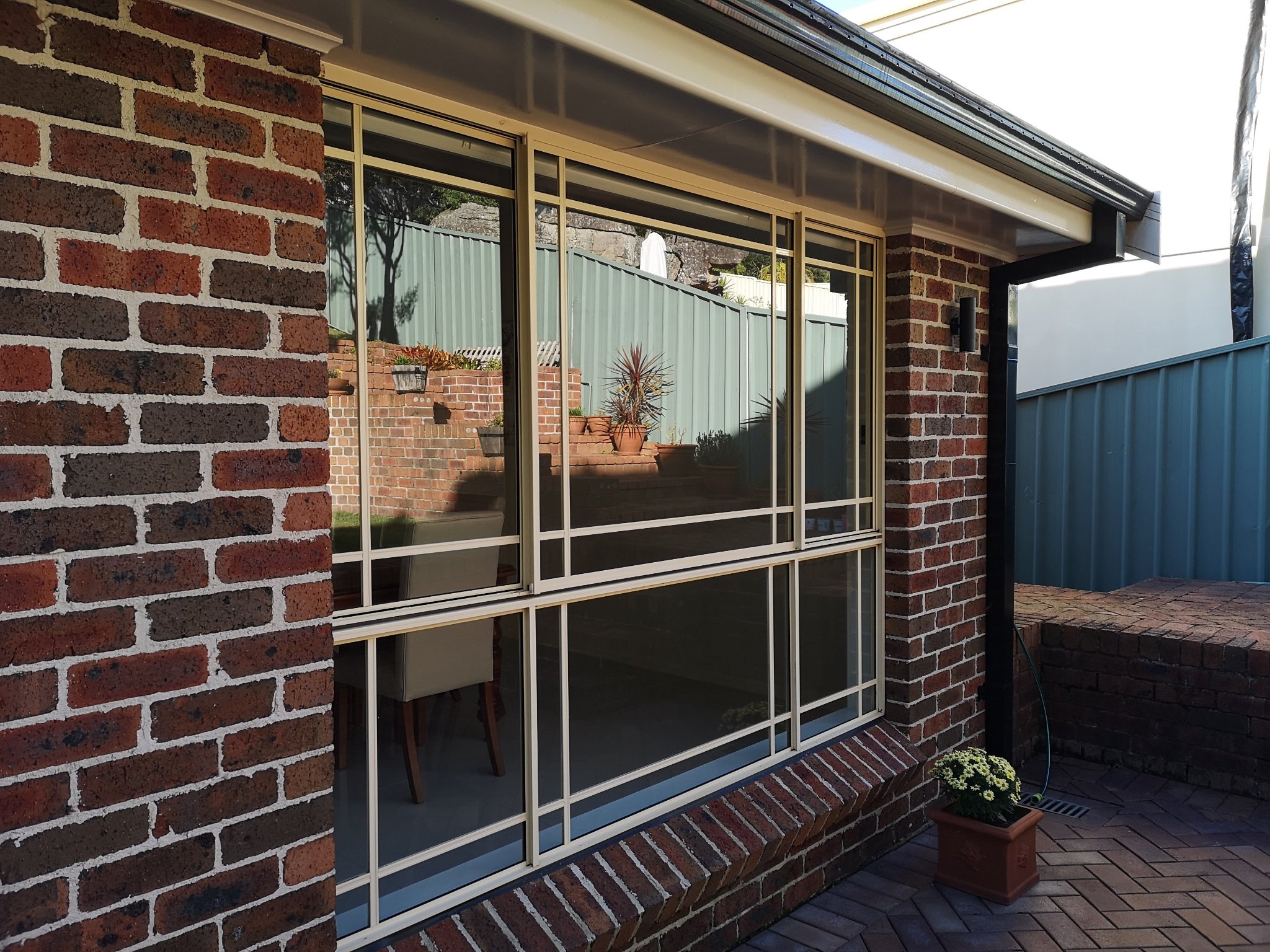 Professional window cleaner using water-fed pole on modern residential home